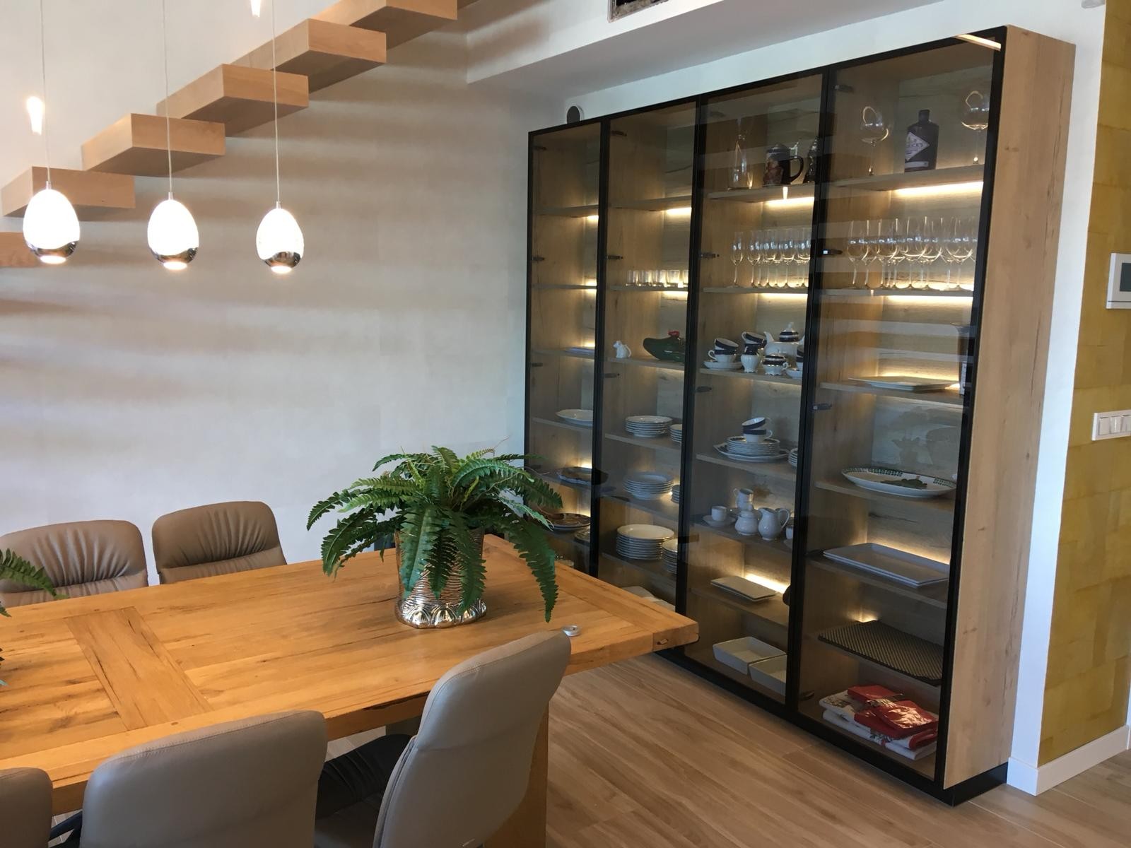 Comedor moderno con vitrina iluminada y mesa de madera